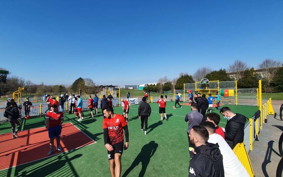 Ambiance sur un city stade StreetFoot, joueurs et public réunis.